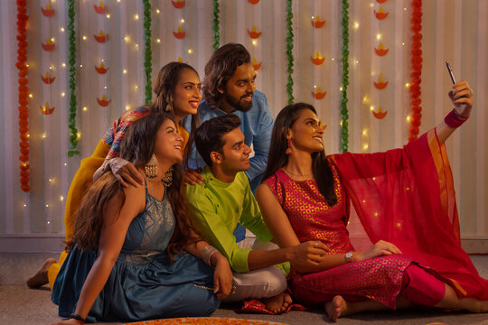 Friends posing for a group Selfie while making Rangoli, during  Diwali celebrations  