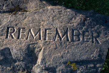 Remember carved into weathered and textured stone block