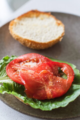 Closeup of burger buns layered with salad leaves and freshly salted tomato slices