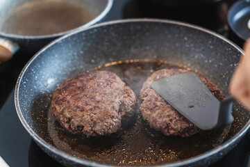 Juicy ground beef hamburger patty sizzling and cooking to perfection inside a frying pan