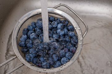 Mycie owoców pod strumieniem zimnej wody z kranu, borówka amerykańska 