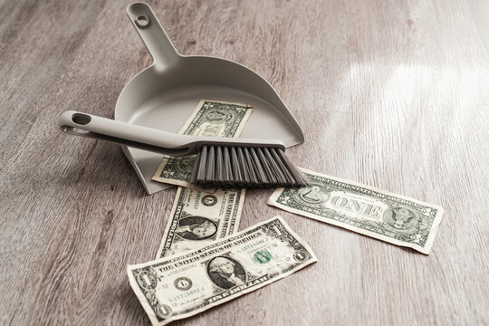 Dustpan and brush alongside scattered one-dollar bills on the floor