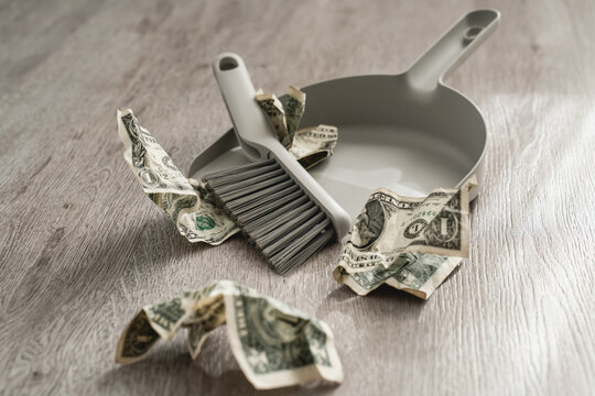 Dustpan and brush alongside scattered one-dollar bills on the floor