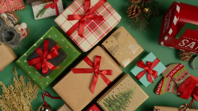 Colorful Christmas and New Year holidays gift boxes on green background. Top down view on rotating table with different present boxes with shiny red satin ribbons RED camera shot. Holidays background