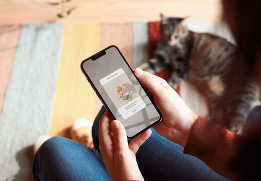 Mockup of woman holding smartphone with customizable screen with cat in background