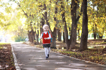 Obraz premium Children with briefcases for a walk in the park. School break. The beginning of the children's studies.
