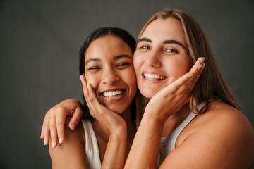 Two lovely happy go luck girlfriends smiling and hugging 