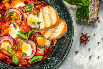 Shakshuka fried eggs, tomatoes, onion, pepper in iron pan, traditional Arabic dish, place for text, top view