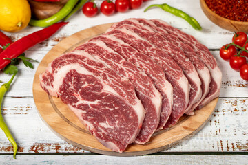 Raw fresh meat ribeye steak on wood background. Raw wagyu ribeye with herbs and spices. Close up