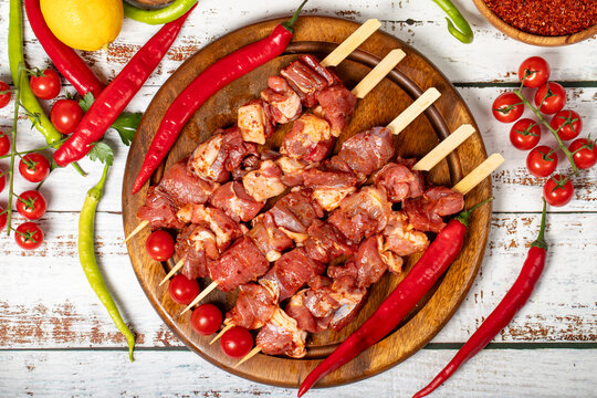 Lamb skewers on wood background. Raw lamb skewer with herbs and spices. Local name kuzu kusleme