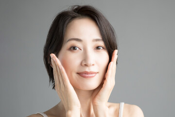 Asian woman in beauty or other beauty image with hands on cheeks (Japanese)Looking at camera Frontal