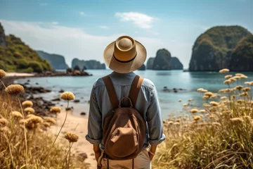 Foto op Canvas Young man in straw hat travel on the beach with mountains , sea background , Tropical travel on vacation Concept © Atchariya63