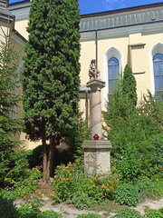 Sculptures of saints surrounded by lush park vegetation near the walls of the church.