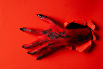 Red female hand with black nails on red background