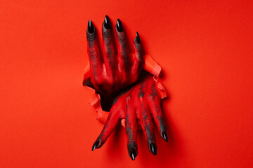 Red female hands with black nails on red background