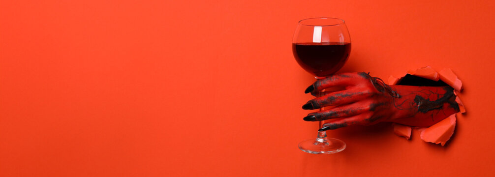 Red female hand with glass of wine on red background, space for text