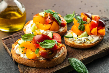 Toast with cream cheese, peaches, tomatoes and green basil leaves. Healthy summer appetizer or snack