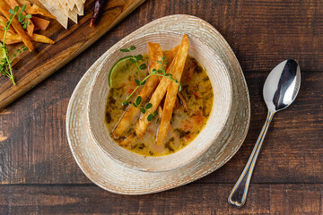 Bowl of tasty Sopa de Lima soup on wooden table