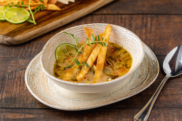 Bowl of tasty Sopa de Lima soup on wooden table