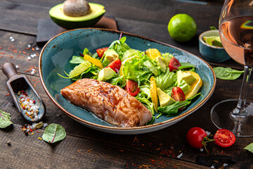 Salmon steak with a salad of vegetables, citrus and herbs. Menu for a restaurant. Beautiful composition on wooden boards.
