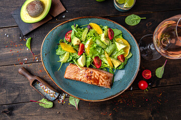 Salmon steak with a salad of vegetables, citrus and herbs. Menu for a restaurant. Beautiful composition on wooden boards.