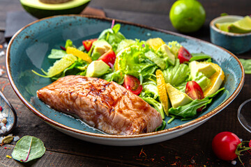 Salmon steak with a salad of vegetables, citrus and herbs. Menu for a restaurant. Beautiful composition on wooden boards.