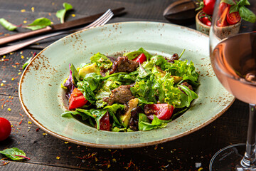 Warm salad with beef and herbs. Menu for a restaurant. Beautiful composition on wooden boards.