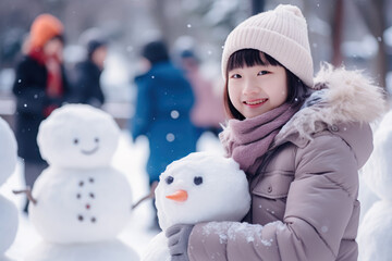 Asian chinese girl building snowman at the crowded park in winter