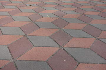 Ornamental geometric pavement made of grey, coral red and maroon concrete tiles
