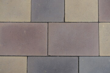 Closeup of pavement made of pink, yellow, brown and grey concrete blocks