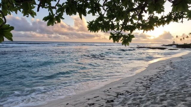 A beautiful orange sunset over a tropical ocean and white sandy beach on the island of Samoa