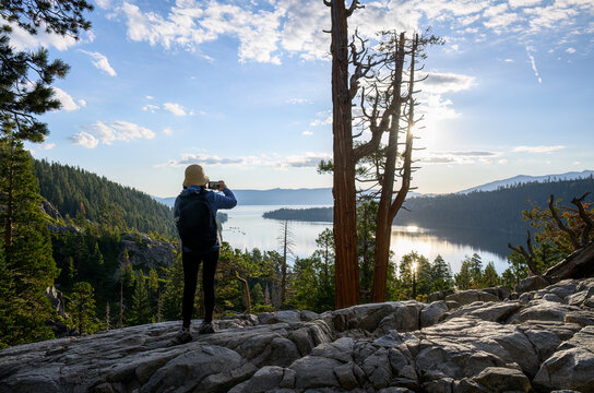Woman taking photos using smartphone at Emerald Bay. South Lake Tahoe at sunrise. California.