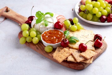 Healthy mediterranean cheese and fruits board on light background