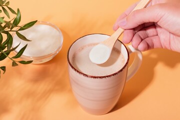 Person Adding Collagen Powder to Coffee