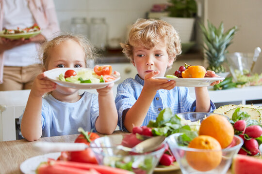 Brother and sister holding salad plates at home