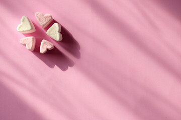 Delicate pink and white marshmallows in the shape of a heart on a pink background with copy space. Valentine's Day symbols tender marshmallow sweets heart shape.