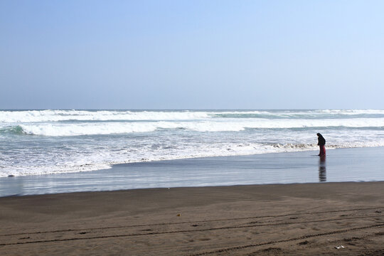 A lady walking alone on Parangtritis beach, Yogyakarta, Indonesia.