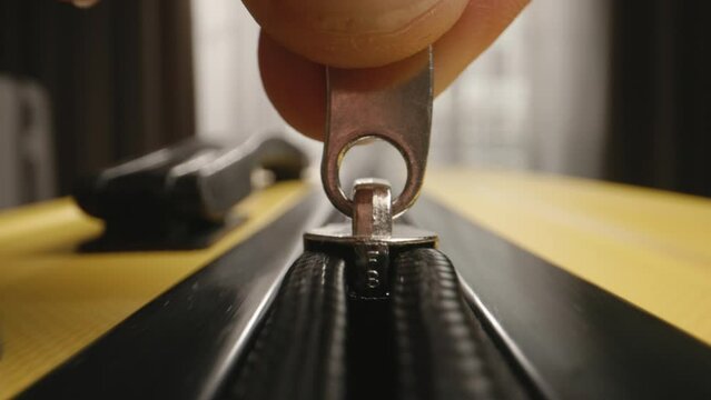 Close up, zipper, fingers zipping suitcase. Unrecognizable fingers slowly fasten zipping zipper on packed luggage baggage suitcase bag. Concept of travel trip journey vacation, preparation for travel.