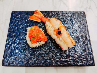 Grilled Shrimp Sushi and Salmon Roe Sushi In a plate. Together, the two sushi contrast in texture and flavor: the tender warmth of shrimp juxtaposed with the cool, popping sensation of roe.