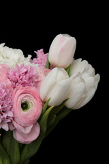 Bouquet of pink ranunculus and white tulips flowers over the black wall