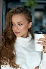 Girl holds cup of coffee. Beautiful young woman drinking cappuccino.