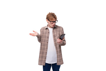 handsome caucasian student guy in glasses is trying to figure out the phone