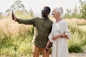 Senior couple making selfie portrait on smartphone while walking outdoors