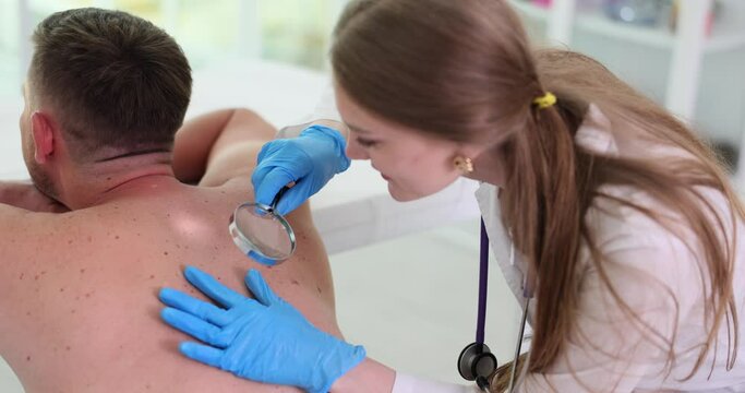 Oncologist examines tumors on skin of adult using magnifying glass. Moles nevi causes and diagnosis