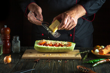 The cook adds cheese to the stuffed squash. The concept of cooking national stuffed zucchini or mahshi in the restaurant kitchen