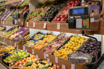 Vista de una frutería en un mercado con una balanza en primer plano.