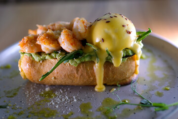 breakfast delicious toast with avocado and eggs Benedict on delicious bread shrimp Parmesan greens appetizing aromatic lunch snack sprinkled with flax grains seeds on gray plate. restaurant serving