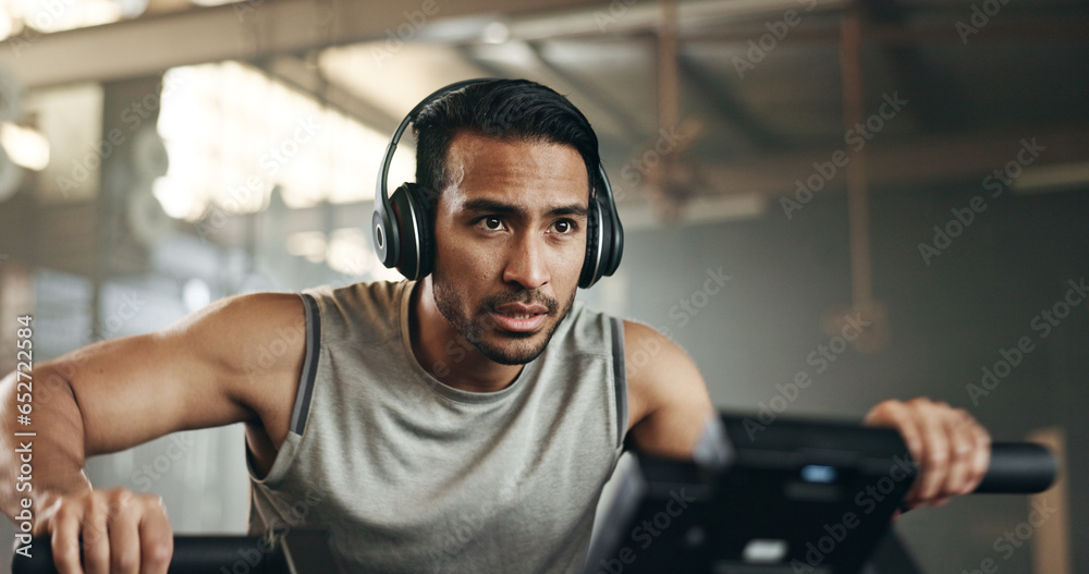 Canvas Prints Asian man, headphones and cycling at gym on machine and listening to music in sports workout or exercise. Serious male person or athlete training on bicycle machine or equipment for healthy cardio