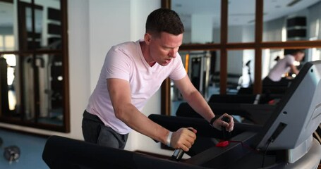 Tired man runs on treadmill in gym. Weight loss concept sport motivation and health