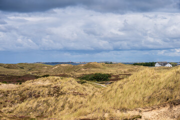 Dramatische Wolken im Dünenbereich der Nordseeinsel Amrum der Blick geht hinüber zur Nachbarinsel Sylt mit dem Leuchtturm von Hörnum